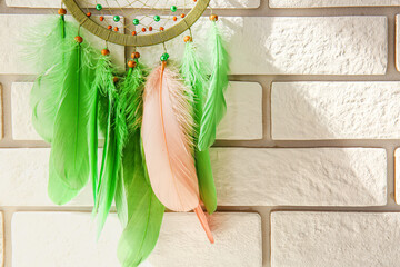 Dream catcher hanging on white brick wall, closeup