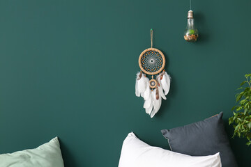 Dream catcher hanging on green wall in bedroom