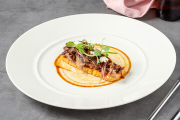Beef bruschetta on a white porcelain plate on a dark gray table