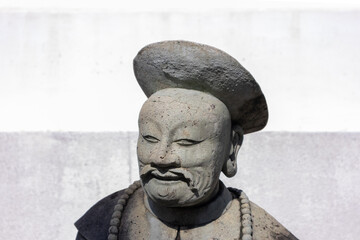 Stone statue of man with moustache in a Buddhist temple with white background