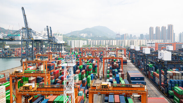 Hong Kong - 01.19.2023 Storage Yard Of Hong Kong International Container Terminal With Gantry Cranes And Big Quantity Of Cargo Containers With City Scape And Sky Scrappers On Background.