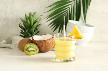 Fototapeta premium Glass of tasty pineapple smoothie, kiwi and coconut on table