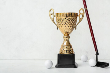 Gold cup with golf club and balls on light background