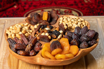 Fototapeta na wymiar Mixed nuts platter. Wood nut plate prepared with hazelnuts, cashews, dates, apricots and grapes.