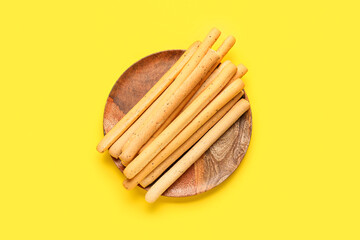 Plate with tasty Italian Grissini on yellow background