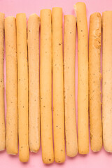 Tasty Italian Grissini on pink background