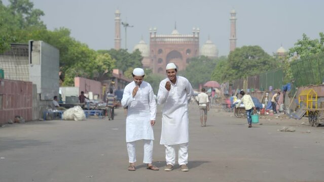 Muslim men doing adab in front of a mosque to the camera