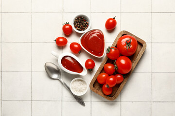 Naklejka na ściany i meble Gravy boat and bowl of tasty ketchup with fresh tomatoes on white tile background