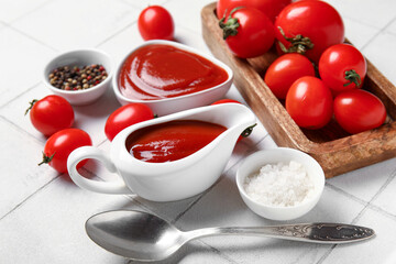 Gravy boat with tasty ketchup and fresh tomatoes on white tile background