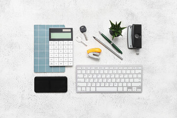 Composition with keyboard, calculator, plant and stapler on white background