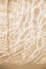 Abstract nature textured background, water waves in the pool with sun reflection. Clear water with bubbles and circles on beige background