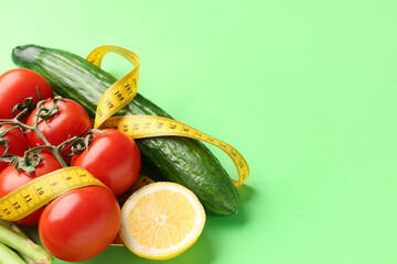 Vegetables, lemon and yellow measuring tape on green background. Diet concept
