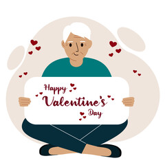 A man sits cross-legged and holds a large card with a congratulation for saint valentine.