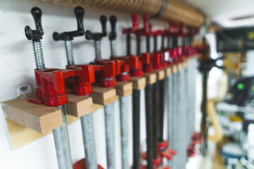 Group of bar clamps used in woodworking for glueing pieces together. Carpenter studio interior. Closeup indoor shot. . High quality photo