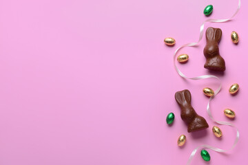 Chocolate bunnies, Easter eggs and ribbon on pink background