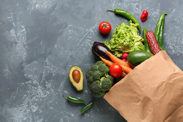 Paper bag with vegetables and sausage on grey grunge background