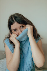 Portrait of young brunette woman in a blue sweater. Trendy casual outfit. Simple minimalistic basic women clothes.