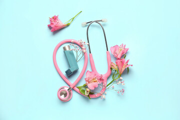 Asthma inhaler with stethoscope and flowers on blue background
