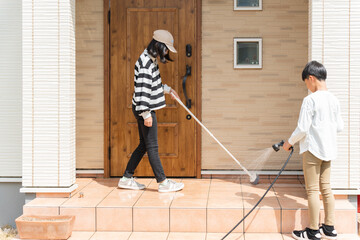 玄関の土間をブラシで掃除をする小学生の男の子と女の子