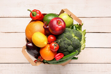 Paper bag with vegetables and fruits on white wooden background