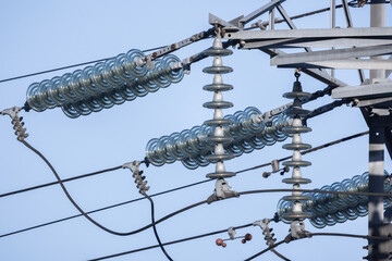 High voltage insulators of overhead power line are under blue sky