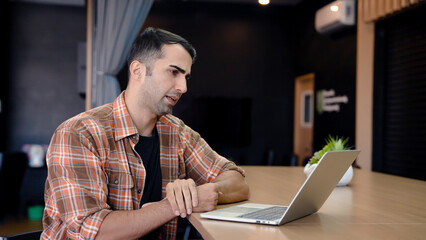 Supervisor is video call on lady computer with employees listen summary work he assigned to do, sit listen intently have serious face color along with giving advice on work get complete job.