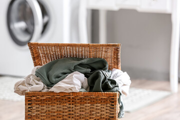 Basket with dirty clothes in laundry room, closeup