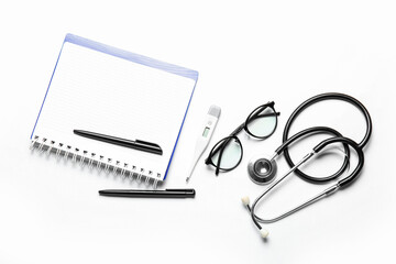 Notebook, stethoscope, glasses and thermometer on white background