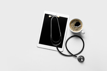Stethoscope, tablet computer and cup of coffee on white background