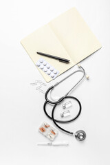 Stethoscope, notebook and drugs on white background