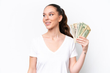 Young caucasian woman taking a lot of money isolated on white background looking side