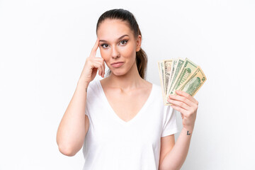 Young caucasian woman taking a lot of money isolated on white background thinking an idea