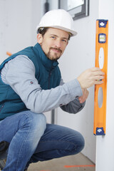 professional worker in helmet is measuring wall with level