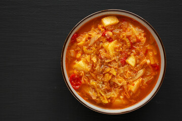 Homemade Shredded Cabbage and Potato Soup in a Bowl on a black background, top view. Overhead, from above, flat lay. Copy space.