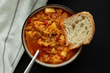Homemade Shredded Cabbage and Potato Soup in a Bowl on a black background, top view. Overhead, from above, flat lay.