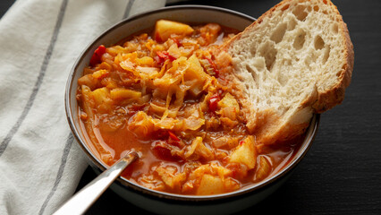 Homemade Shredded Cabbage and Potato Soup in a Bowl on a black background, side view.