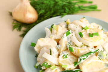 Plate of tasty Potato Salad with greens on yellow background, closeup
