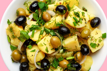 Bowl of tasty Potato Salad with vegetables on pink background, closeup