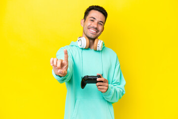 Young handsome man playing with a video game controller over isolated wall showing and lifting a finger