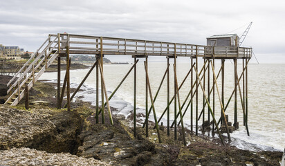 Fototapeta na wymiar Fisherman's hut made of wood and resting on piles along the Atlantic ocean's coastline during a cloudy day