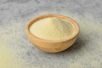 Bowl of raw semolina on grunge background