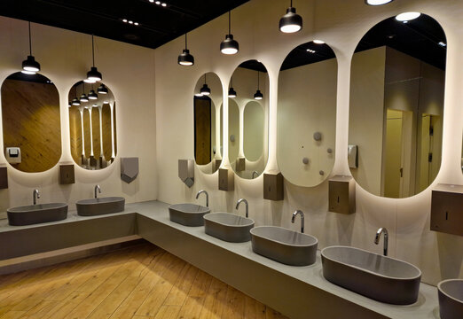 modern public toilet interior. empty public bathroom with sinks and wide wall mirrors.