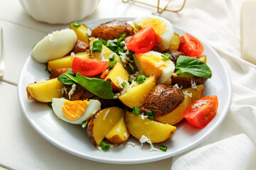 Plate of tasty potato salad with eggs and tomatoes on light wooden background