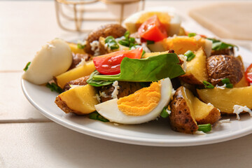 Plate of tasty potato salad with eggs and tomatoes on light wooden background, closeup