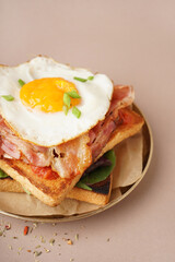 Delicious sandwich with fried egg and bacon on beige background