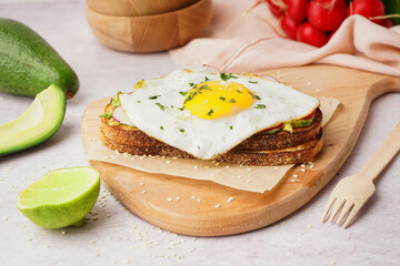 Delicious sandwich with fried egg on light background