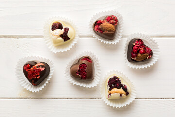 chocolate sweets in the form of a heart with fruits and nuts on a colored background. top view with space for text, holiday concept