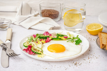 Plate with tasty fried egg and salad on light table