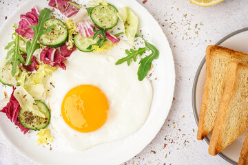 Plate with tasty fried egg, toast and salad on light table