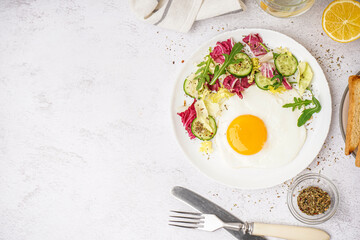 Plate with tasty fried egg and salad on light table
